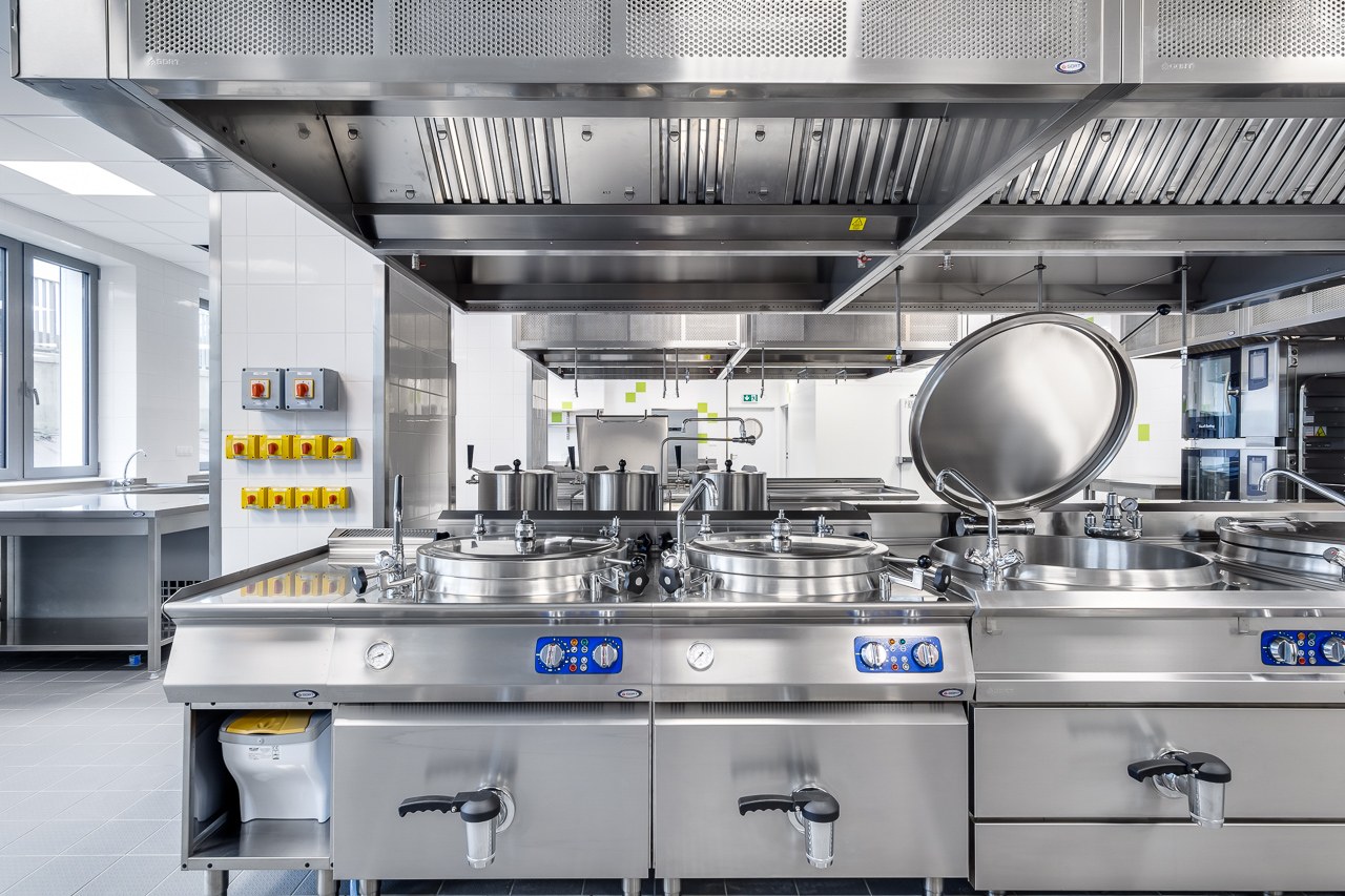 Stainless-steel professional kitchen with bratt pans, kettles and ventilation hoods — hospital catering facility in Poznań delivered by GORT